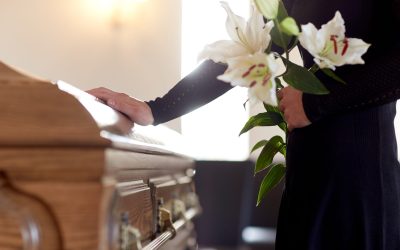 people and mourning concept - woman with white lily flowers and coffin at funeral in church